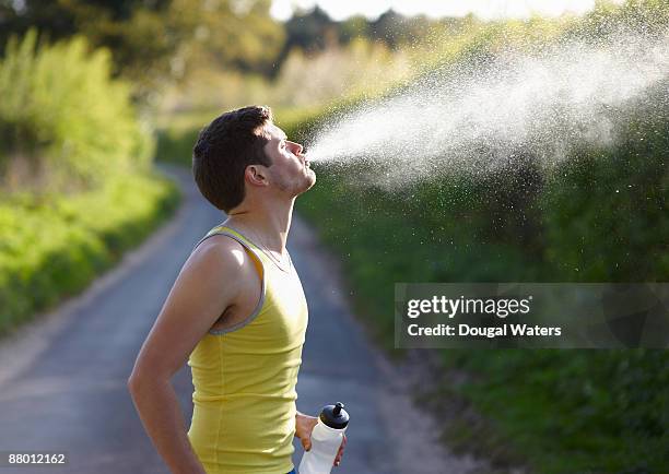 young runner spitting out water. - spitting water stock pictures, royalty-free photos & images