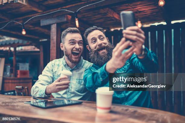 two bearded friends drinking coffee and taking selfie in cafe - novembro azul imagens e fotografias de stock