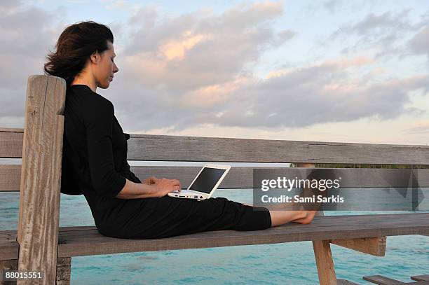 woman on notebook, on wooden jetty, at sunrise - isla de mabul fotografías e imágenes de stock