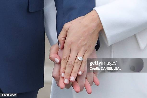 Britain's Prince Harry stands with his fiancée US actress Meghan Markle as she shows off her engagement ring whilst they pose for a photograph in the...