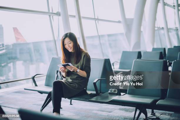 young asian woman holding passport and boarding pass on hand waiting in the departure lounge in airport - lounge chair bildbanksfoton och bilder