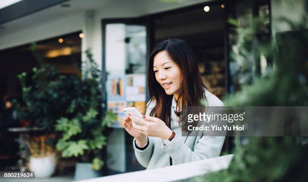 beautiful asian lady using smartphone and relaxing in outdoor cafe - yiu yu hoi stock pictures, royalty-free photos & images