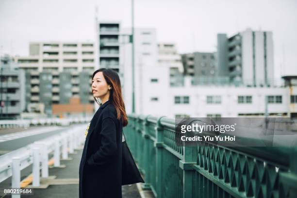 young confident businesswoman walking in city against urban cityscape - yiu yu hoi stock pictures, royalty-free photos & images