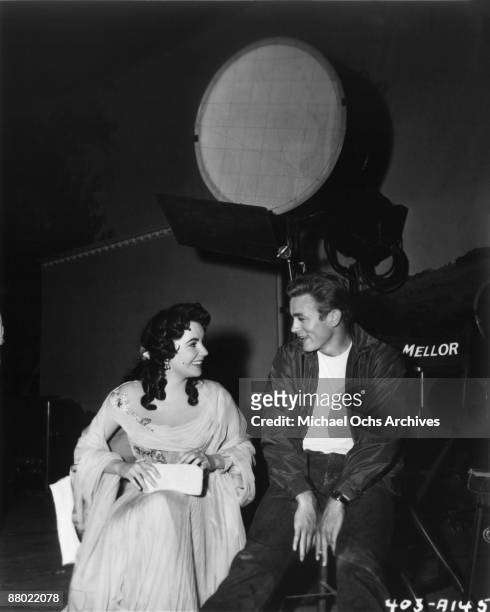 Actors James Dean and Elizabeth Taylor chat on the set of the Warner Bros film 'Giant' in 1955 in Los Angeles, California. Dean has on the jacket he...