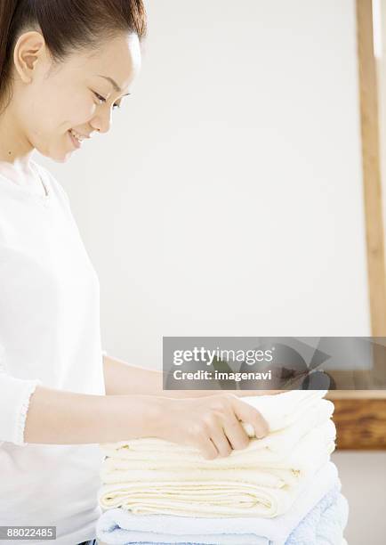 a woman folding towel - woman smiling facing down stock pictures, royalty-free photos & images