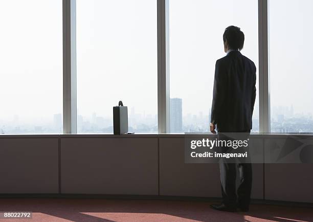 businessman looking out of window - ビジネスフォーマル ストックフォトと画像