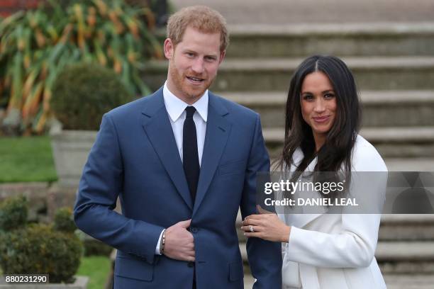 Britain's Prince Harry stands with his fiancée US actress Meghan Markle as she shows off her engagement ring whilst they pose for a photograph in the...