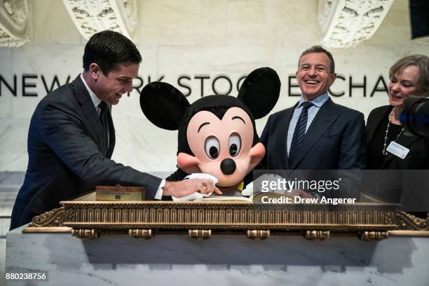 Mickey Mouse and chief executive officer and chairman of The Walt Disney Company Bob Iger sign the guest book before ringing the opening bell at the...