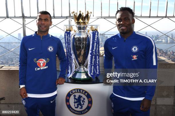 Former Chelsea FC players Ashley Cole and Michael Essien pose with the UK Premier League Trophy during visit to the Empire State Building Observatory...