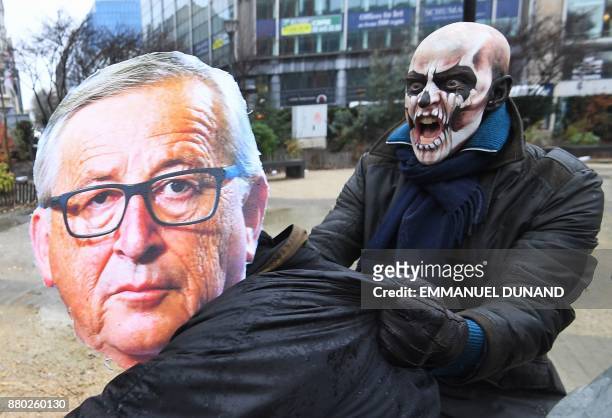 Activists acting as European Commission President Jean-Claude Juncker and a Monsanto-character with his face painted with a skull enact a tug-of-war...