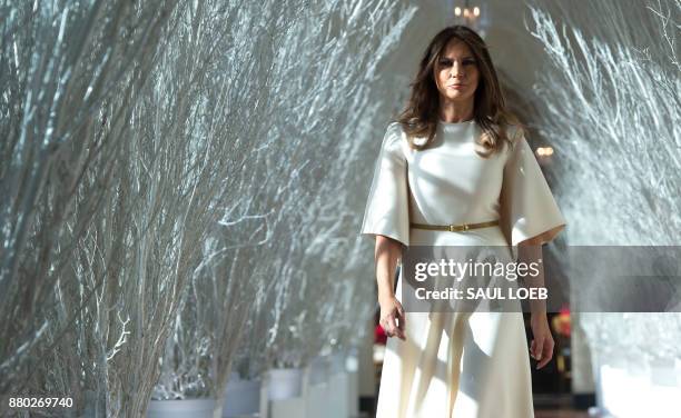 First Lady Melania Trump walks through Christmas decorations in the East Wing as she tours holiday decorations at the White House in Washington, DC,...