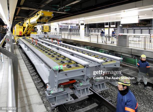 Workers install a bridge beam after pebbles were removed from under the Tokaido Shinkansen Line rail tracks in preparation for the construction of a...