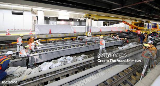 Workers install a bridge beam after pebbles were removed from under the Tokaido Shinkansen Line rail tracks in preparation for the construction of a...