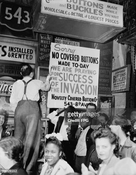 New York haberdasher fixing up a sign explaining that his shop will be closed while staff pray for Allied victory in the invasion of Normandy on...