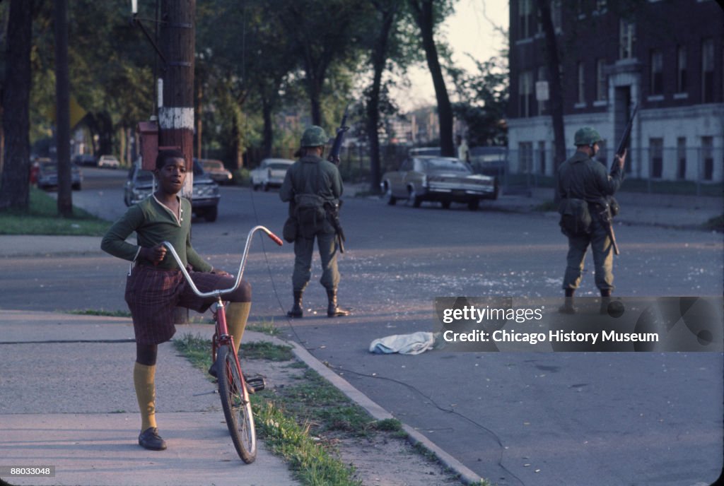 Chicago Riots 1968 Book National Guardsmen stand guard as a young boy pauses from riding his ...
