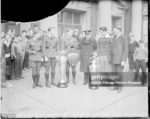 Full-length portrait of John Philip Sousa, American composer and bandmaster, standing with a group of young men in front of Tilden High School,...