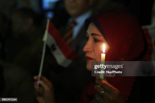 People take part during a candlelight vigil as they hold national flags for victims of a Friday mosque attack at the Journalists Syndicate, in Cairo,...