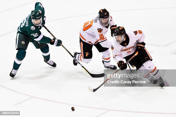 Zach Whitecloud of the Bemidji State Beavers, Jackson Cressey and Max Becker of the Princeton Tigers eye the puck during the first period at Hobey...