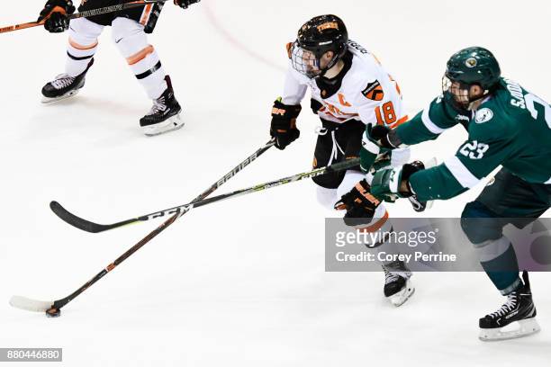 Eric Robinson of the Princeton Tigers handles the puck while being pressured by Hampus Sjödahl of the Bemidji State Beavers during the first period...
