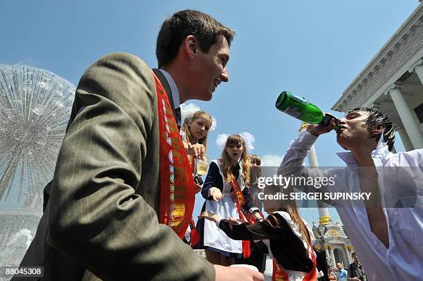 Schoolboys and schoolgirls drink champagne in a fountain during a traditional gathering of school graduates on Independence Square in Kiev on May 29,...