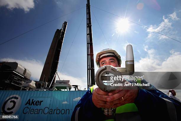 Scientist holds a pressure monitor, beside a new carbon capture test unit at Longanet power station on May 29, 2009 in Longanet, Scotland. The new...