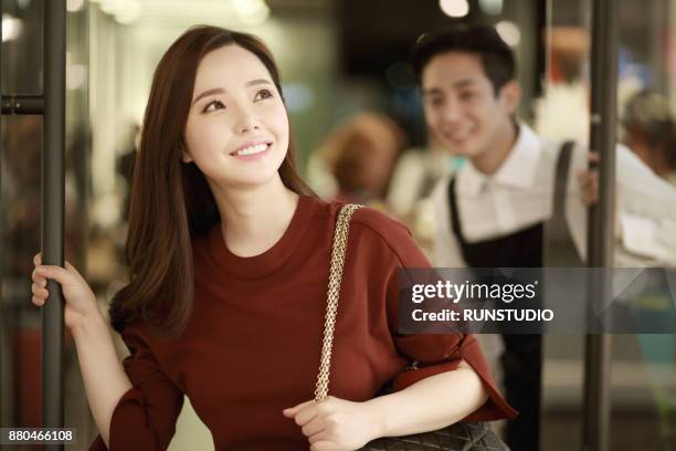 young woman opening hair salon door and looking very happy - purses and body care stock pictures, royalty-free photos & images