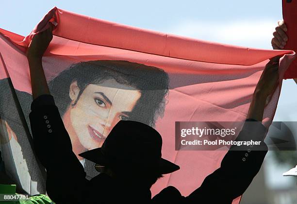 Fan holds up a banner of US pop star Michael Jackson in front of the gates of the Santa Barbara County Courthouse in Santa Maria, CA, on Thursday,...