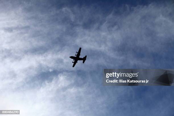 silhouette of airplaine against cloudy blue sky - katsouras stock-fotos und bilder