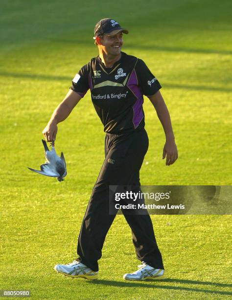 Jacques Rudolph of Yorkshire removes a pigeon from the pitch, after his throw hit it during the Twenty20 Cup match between Yorkshire and Lancashire...