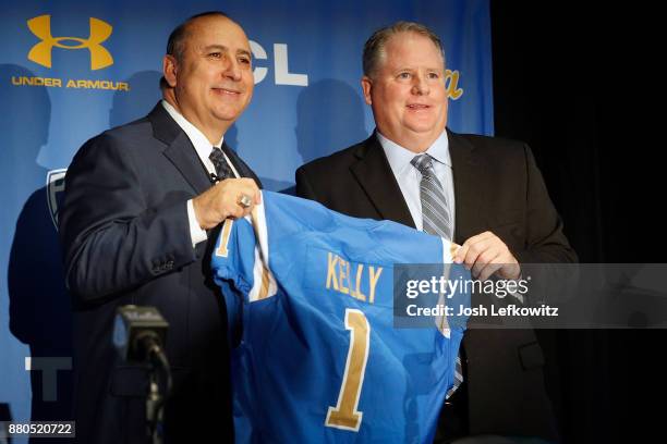 Director of Athletics Dan Guerrero and Chip Kelly hold up a jersey during a press conference introducing Kelly as the new UCLA Football head coach on...