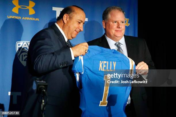Director of Athletics Dan Guerrero and Chip Kelly hold up a jersey during a press conference introducing Kelly as the new UCLA Football head coach on...