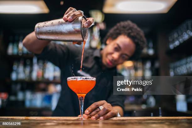 young bartender pouring cocktails in a cocktail bar - cocktail shaker stock pictures, royalty-free photos & images