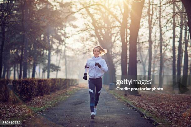 young woman is running in the cold foggy morning - running stock pictures, royalty-free photos & images