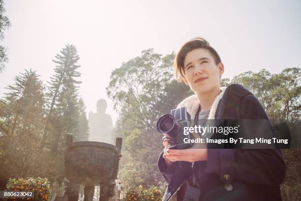 young caucasian woman talking pictures with vintage film camera in ngong ping in hong kong. - ngong stockfoto's en -beelden