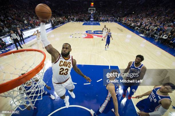 LeBron James of the Cleveland Cavaliers dunks the ball past Robert Covington, Dario Saric, Joel Embiid, and Ben Simmons of the Philadelphia 76ers in...