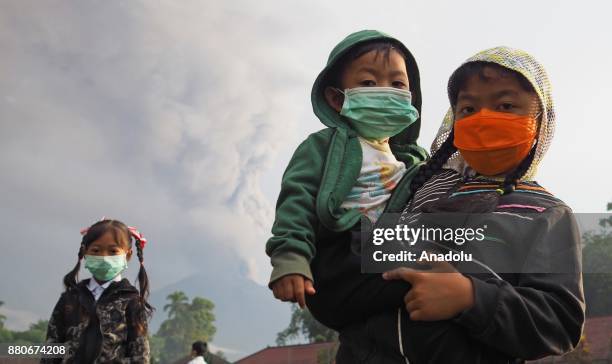 Elementary school students with face masks pose for a photo in a school ground before school in Rendang village of Karangasem, Bali, Indonesia on...