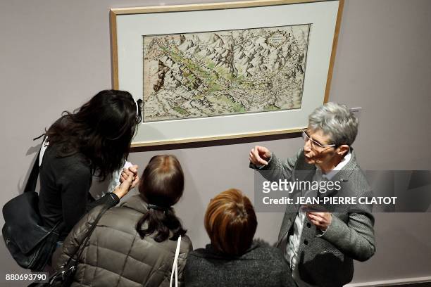 People listen to explanations from a guide as they visit the exhibition "Les Alpes de Jean de Beins - Des cartes aux paysages " at the Ancien Eveche...