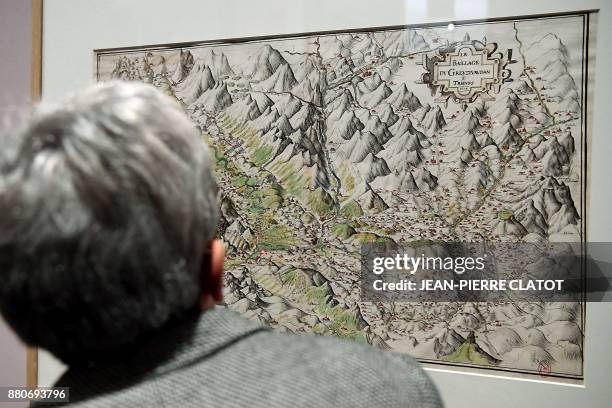 Person looks at ancient maps on display at the exhibition "Les Alpes de Jean de Beins - Des cartes aux paysages " at the Ancien Eveche museum on...