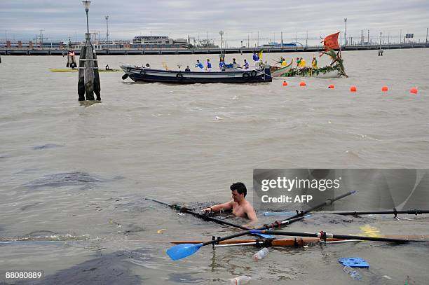 Participant stands in the water after his boat drowned during the 35th Vogalonga rowing boats regatta on Venice's canals on May 31, 2009. Competitors...