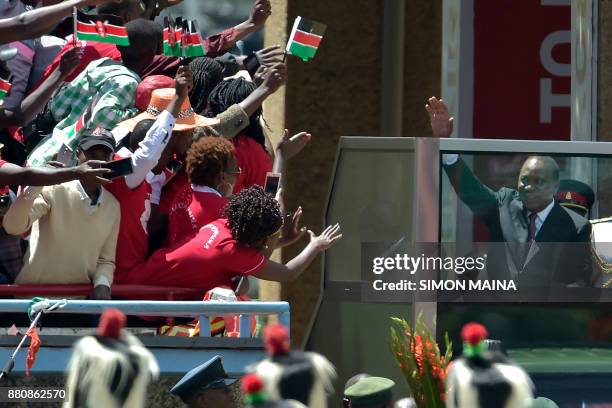 Kenya's President Uhuru Kenyatta waves to supporters as he arrives to take oath of office during his inauguration ceremony at Kasarani Stadium on...