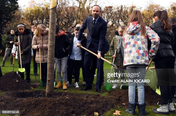 French Prime Minister Edouard Philippe plants an apple tree with pupils from the primary school of Theophile Gautier in le Havre, in the garden of...