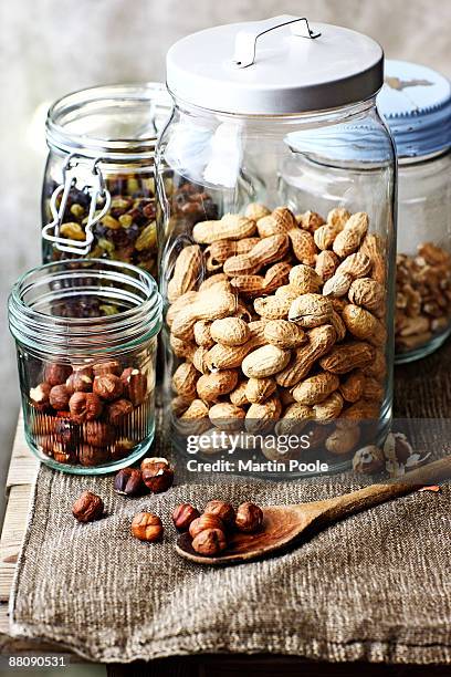 jars of nuts and raisins on table - nuts stock pictures, royalty-free photos & images