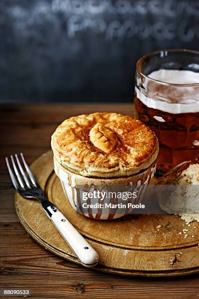 meat pie on bread board with pint of bitter - meat pie stockfoto's en -beelden