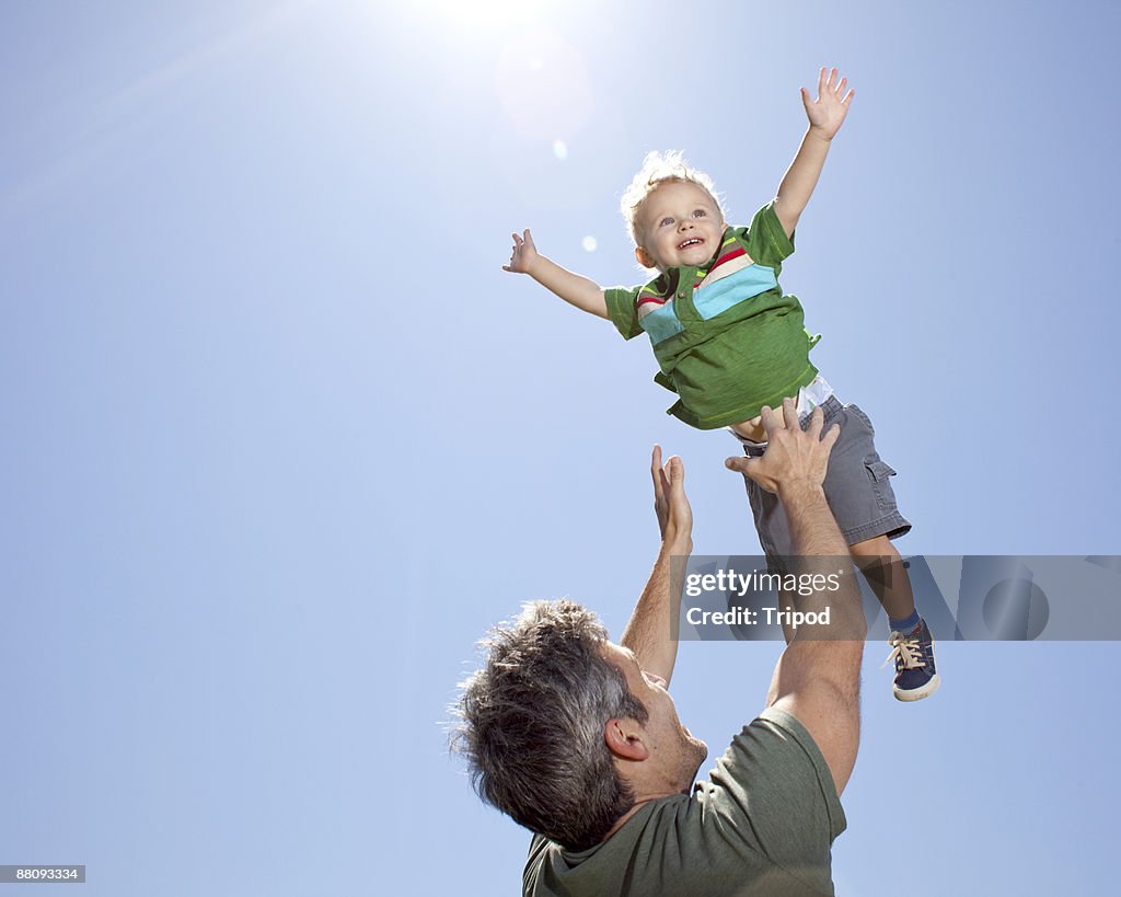 Father tossing son in air