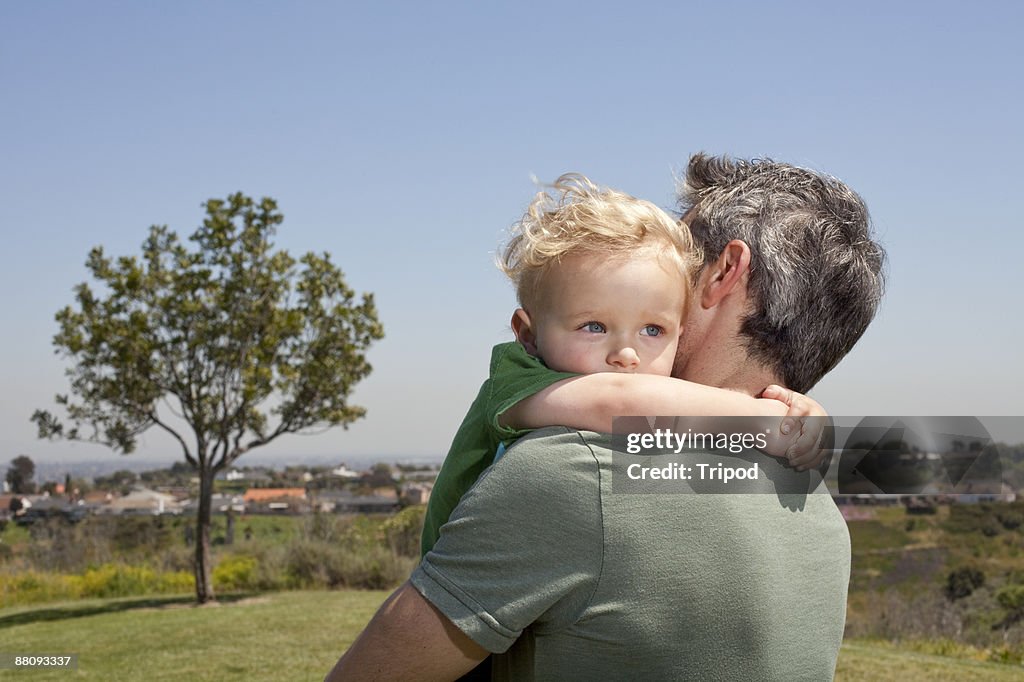 Father holding son in arms outdoors