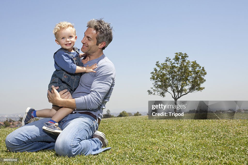 Father and son sitting on grass together