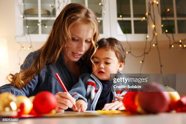 woman making christmas drawings with her son - christmas colouring stock pictures, royalty-free photos & images