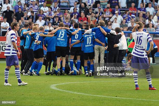 Marvin Braun and Fiete Sykora of Osnabrueck look dejected while players of Paderborn celebrate the ascension to the Second Bundesliga after the...