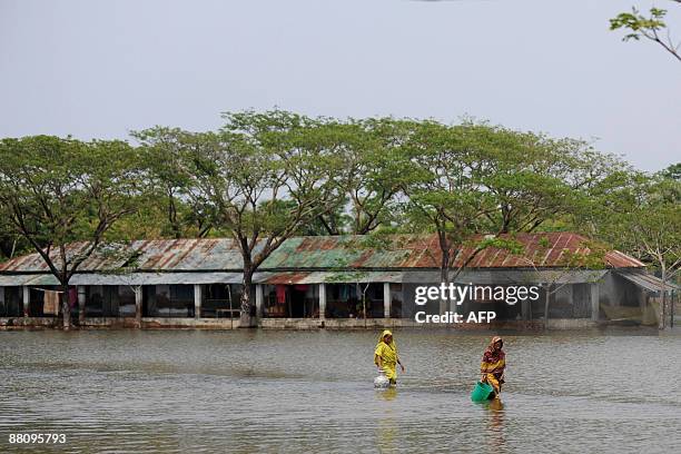 Bangladeshi villagers wade through floodwater as they go to collect drinking water on the outskirts of Khulna some 400kms from Dhaka on June 1, 2009....