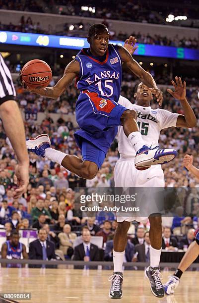 Tyshawn Taylor of the Kansas Jayhawks looks to pass the ball in midair against Durrell Summers of the Michigan State Spartans during the third round...